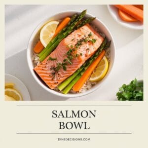 A bright photo of a perfectly cooked Salmon Bowl, served on a bed of rice and garnished with fresh herbs and lemon wedges. Simple sides of asparagus and carrots are arranged around the salmon. The clean, white background highlights the dish, with the title "Salmon Bowl" in bold text and the footer reading "dinedecisions.com".